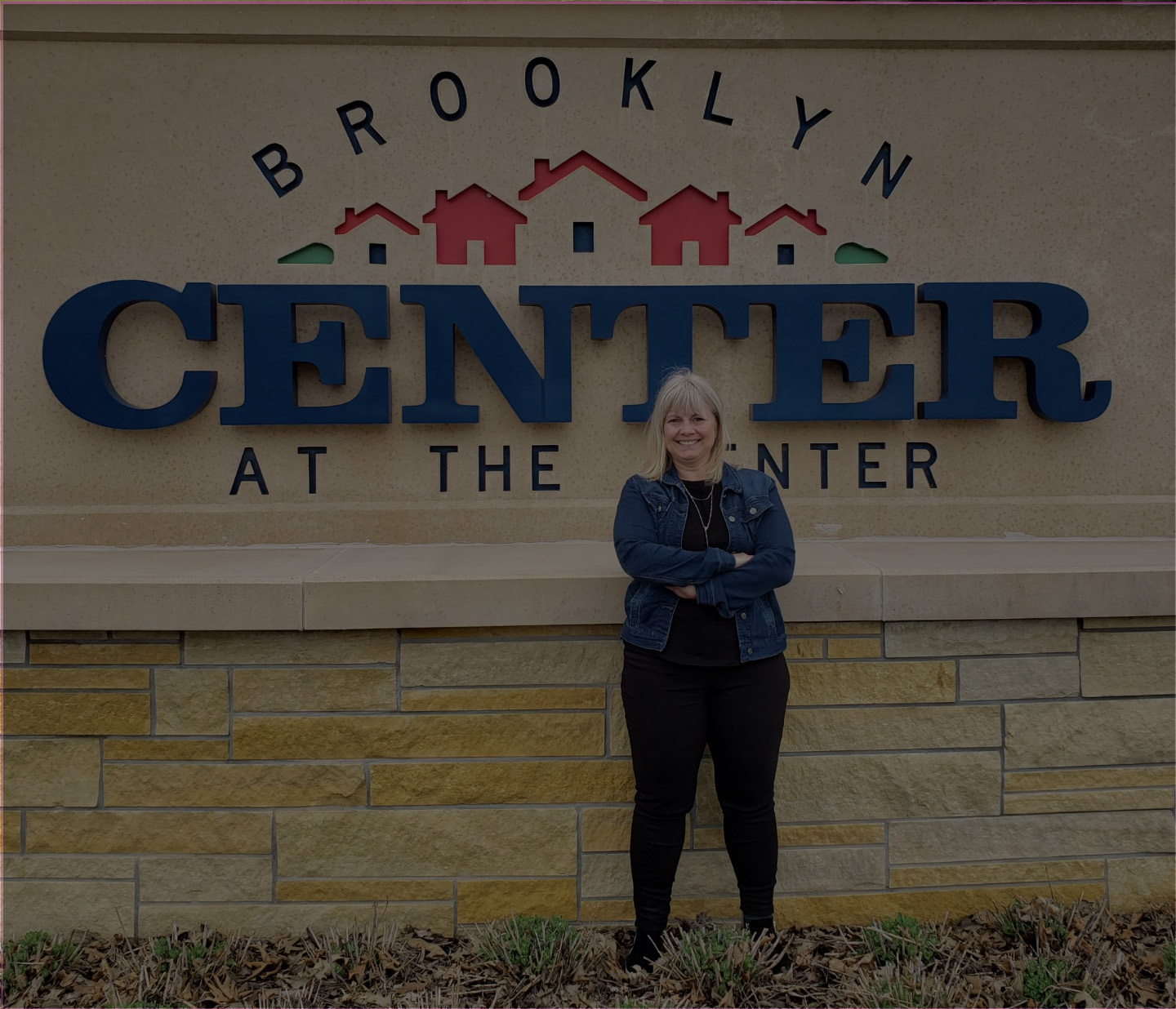 Gretchen Enger standing in front of Brooklyn Center city sign